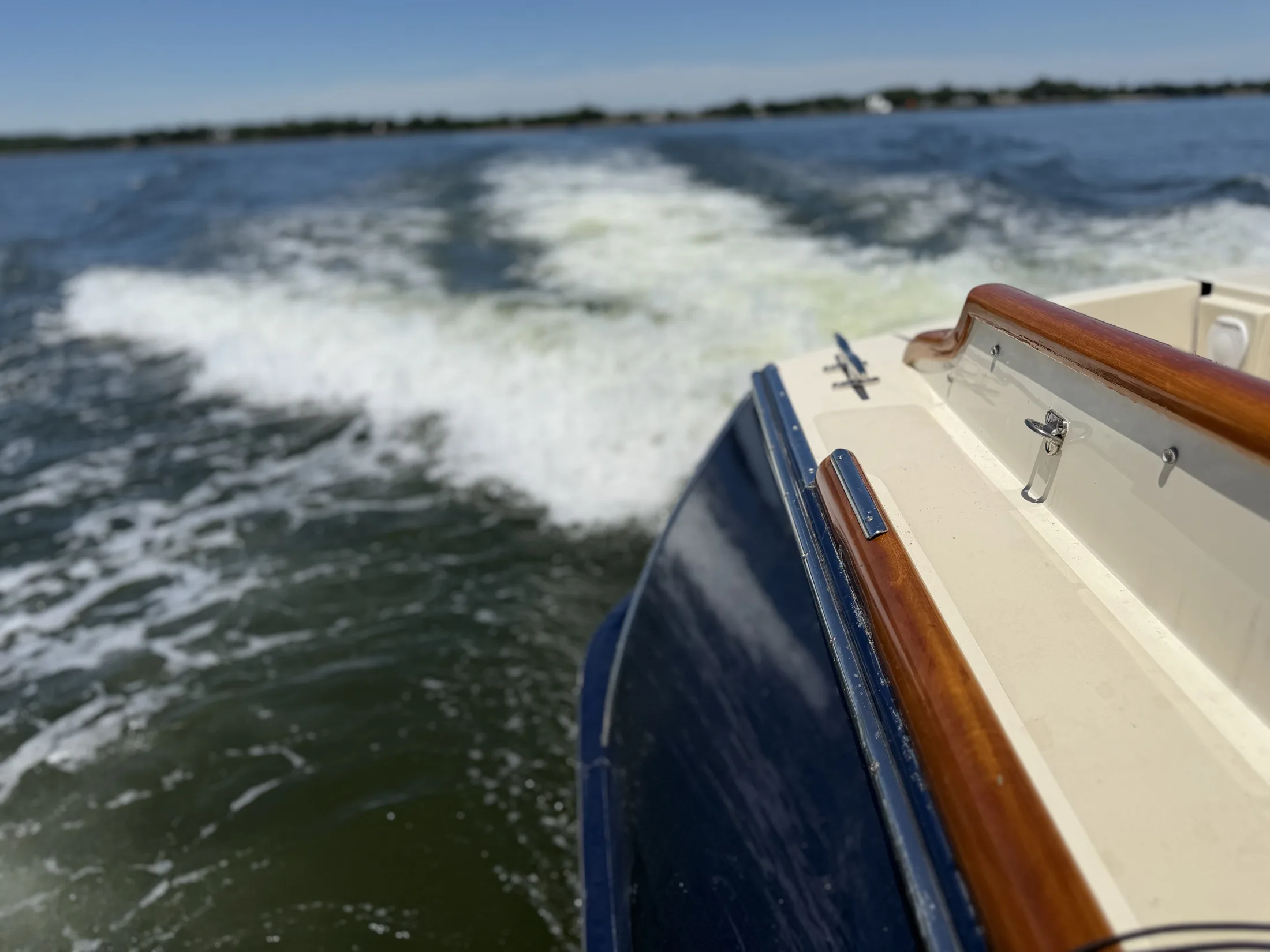 Wake off the varnished rail of a boat underway